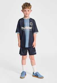 Marinblått och ljusblått sportset för barn med kortärmad tröja, matchande shorts och blå sneakers med ljusbruna sulor.