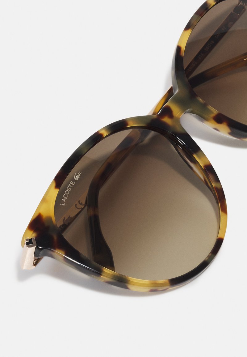 Occhiali da sole tartarugati con forma a occhialino, lenti sfumate marroni e dettagli in tonalità dorata sulle tempie. Logo sulla parte interna dell'asta.