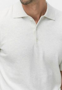 Lichtgrijze poloshirt van zachte stof, met een klassieke kraag, drie-knopen sluiting en korte mouwen. Geen structuur, minimalistisch ontwerp.