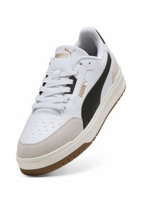 Baskets blanches avec un accent noir, orteil en suède gris et logo doré. Comprend un système de laçage blanc, une tige en cuir synthétique et une semelle en caoutchouc.