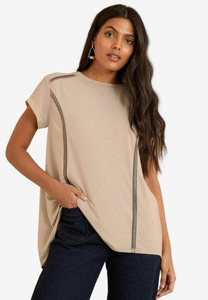 Top corto a maniche corte beige chiaro con scollatura a barca, caratterizzato da dettagli di cucitura scura a contrasto lungo i lati e una vestibilità comoda.