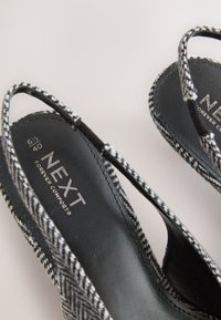 Juodai baltos raštuotos slingback stiliaus basutės su juodais pado vidumi, pažymėtu „NEXT Forever Comfort“, dydis 6½/40.