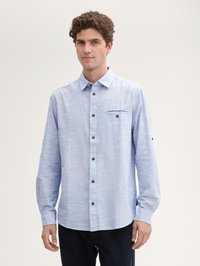 Chemise à boutons à manches longues bleu clair en tissu texturé, dotée d'une poche poitrine et de boutons marron. Coupe ajustée avec un ourlet arrondi.