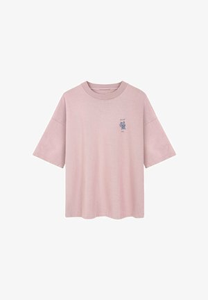 Różowa bawełniana koszulka z luźnym krojem, krótkimi rękawami i małym niebieskim grafikiem na lewym piersi. Okrągły dekolt i miękka faktura.