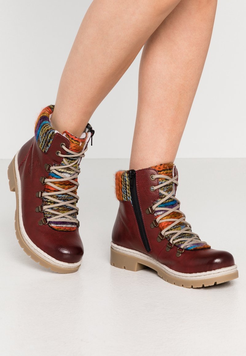 Botas de cuero marrón hasta el tobillo con un colorido cuello de punto y un diseño de cordones. Cremallera lateral para ponerlas y quitarlas fácilmente. Suela resistente para mayor tracción.