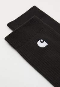 Calze nere a coste realizzate in tessuto, con un logo a spirale ricamato bianco sul risvolto. Design semplice e senza cuciture, privo di motivi.