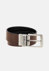 Brauner Ledergürtel mit einer silbernen Metallschnalle, auf der "GUESS" geprägt ist. Der Gürtel hat eine glatte Textur und ein breites Design.