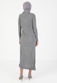 Gray ribbed long dress with long sleeves and a slim fit, featuring a straight hem and side slit, paired with gray high-heeled shoes.