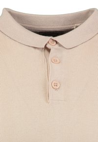 Polo beige con una texture a coste, dotata di un colletto classico e quattro bottoni chiari sulla patta.
