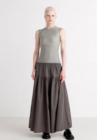 Haut sans manches gris au design ajusté, associé à une longue jupe fluide gris foncé avec une taille froncée et une texture lisse.