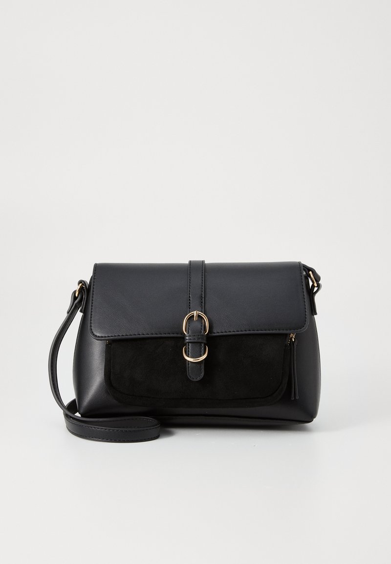 Sac à main en cuir et daim noir avec un dessus plat, une bandoulière détachable, des accessoires en or et une fermeture à pression magnétique.