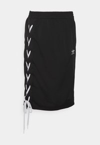 Gonna nera al ginocchio con dettaglio in pizzo bianco sulla parte sinistra e piccolo logo Adidas bianco sul davanti a destra.