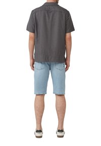 Kurzarmhemd mit Kragen in Dunkelgrau mit einem dezenten Muster; kombiniert mit hellblauen Denimshorts. Legere Schuhe runden das Outfit ab.