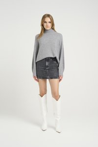 Grijze gebreide coltrui, zwarte denim minirok en witte hoge laarzen met hakken, een spitse neus en een uniek ontwerp aan de bovenrand.