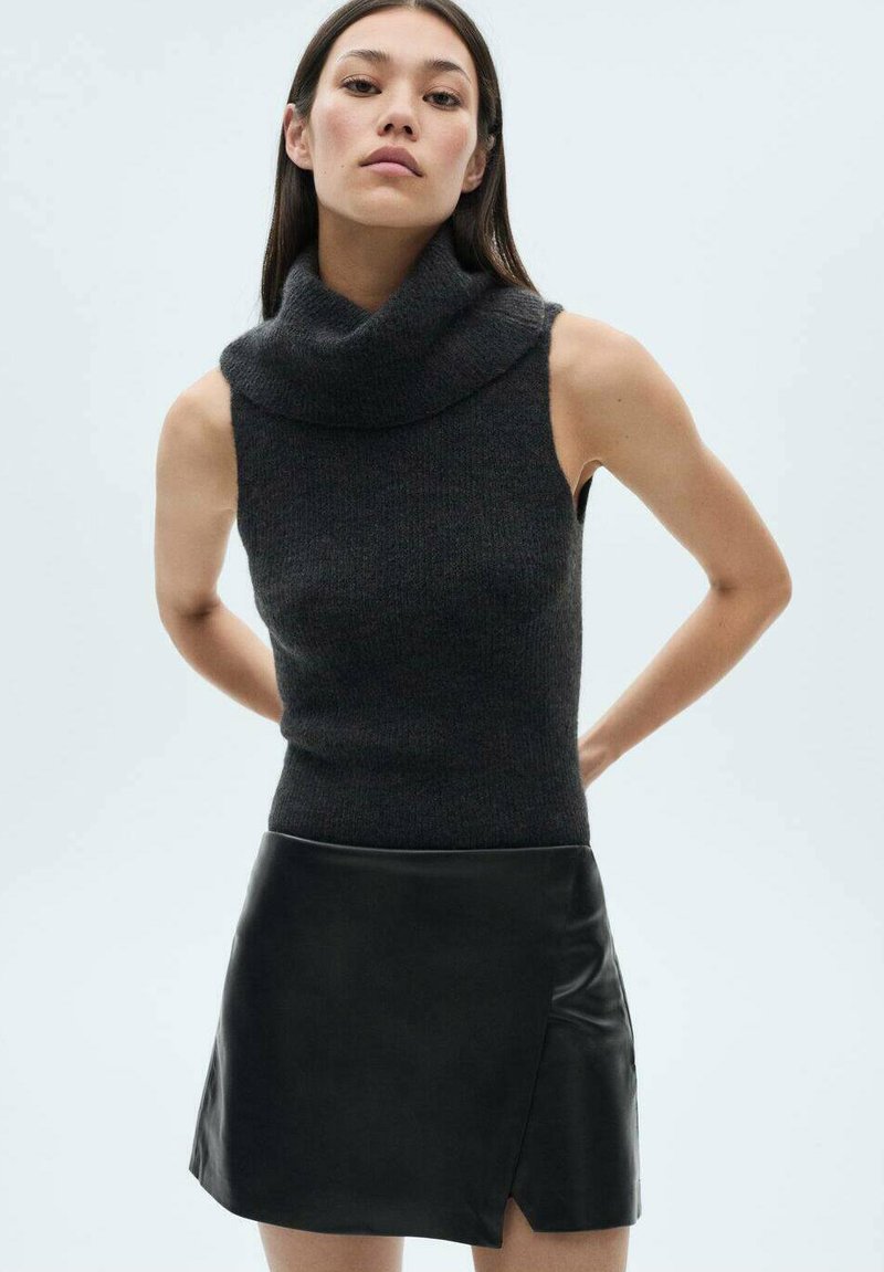 Sleeveless dark grey knitted top with a high cowl neckline, paired with a black leather mini skirt featuring a diagonal slit.