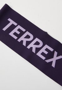 Ljubičasti tkaninski trak s natpisom "TERREX" u velikim, svijetloplavim slovima. Glatka tekstura i pravokutni oblik.