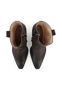 Stivali alla caviglia in suede marrone con punta affusolata, dotati di hardware nero e interno liscio. Dettagli di cucitura sottile lungo i lati.