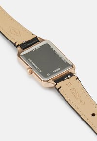 Quarz-Uhr mit einem Gehäuse aus roségoldfarbenem Edelstahl und einem schwarzen Lederarmband. Verfügt über ein minimalistisches schwarzes Zifferblatt und ein geprägtes Logo auf dem Band.