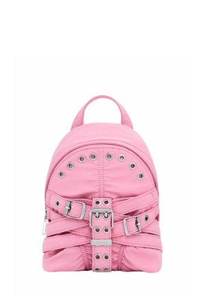 Vaaleanpunainen reppu, jossa on hopeiset soljet, rei'itykset ja ristikkäiset hihnat edessä. Repussa on yläpisto ja vetskari.