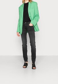 Grön oversized blazer, svart åtsittande t-shirt, mörka jeans och svarta öppna heels. Slinky tyg med en strukturerad siluett.