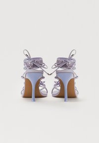Sandales à talons hauts lavande avec des fines brides, une finition lisse et des détails ornementaux à l'arrière. Bout pointu et talon aiguille élancé.