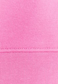 Helles rosa Gewebe mit glatter Textur und gerippten Akzenten am unteren Rand. Gerade Nähte entlang der Naht.