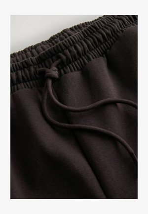 Zwarte sweatpants met een elastische tailleband en een koord. De stof heeft een zachte, gladde textuur en een relaxed fit.