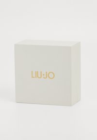 Weißes strukturiertes Kästchen mit glatter Oberfläche, auf der Vorderseite mit dem eingeprägten goldenen Logo "LIU·JO", quadratische Form mit klaren Kanten.