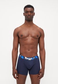 Mörkblå boxer shorts i mjukt tyg, med ett blommönstrat midjeband och "Levi's"-logotyp i vitt. Slät, figurnära design.