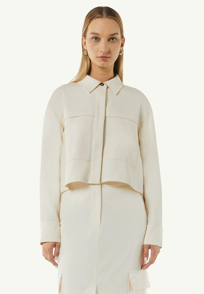 Przycięta, kremowa koszula z guzikami, z dwiema kieszeniami z przodu, długimi rękawami i klasycznym kołnierzykiem, wykonana z gładkiego materia�łu.