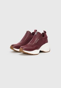 Burgundy athletic shoes with a smooth leather upper, mesh panels, zip closure, and a white, chunky rubber sole.