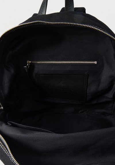 Mustan repun sisusta, jossa näkyy vetoketjullinen tasku, avoin lokero ja nahkahihnat yläosassa.