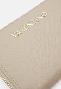 Beige, strukturerad läderplånbok med ett guldmetall-"VALENTINO"-logotyp, med dragkedjestängning och släta sömmar.