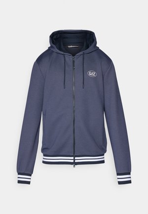 Navy zip-up hoodie in textured fabric, featuring a drawstring hood, white striped accents on cuffs and hem, and a circular logo on the chest.