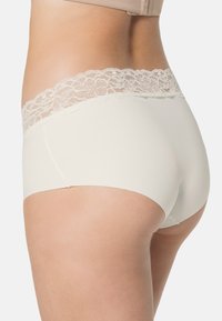 Romantische boyshorts in crèmekleur met kantafwerking, gemaakt van een gladde stof, met een gemiddelde tailleband en een naadloze snit rond de benen.