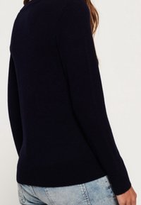 Laivastonsininen neulepaita, pyöreällä kaula-aukolla, pitkillä hihoilla ja istuvalla siluetilla, esitetty takaa. Sileä rakenne ja pehmeä kangas.
