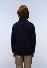 Felpa blu navy con scollo a giro e maniche lunghe, caratterizzata da polsini e orlo a costine. Indossata con pantaloni cargo khaki.
