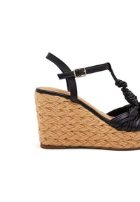 Sandalo con zeppa in pelle nera e platform in juta tessuta, caratterizzato da un design superiore intrecciato e una cinghia alla caviglia con una fibbia dorata.