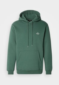 Sweat à capuche vert foncé avec poche avant et cordons, avec petit texte blanc « Mads Nørgaard Copenhagen » sur la poitrine.