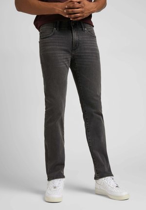 Jeans in denim grigio scuro da uomo con una vestibilità dritta, una leggera texture sbiadita, design a cinque tasche, abbinati a sneakers bianche.