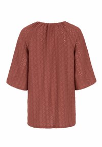 Rustfarvet bluse med rund hals og korte ærmer, der har et tekstureret eyelet-mønster og subtilt samling ved halsudskæringen.