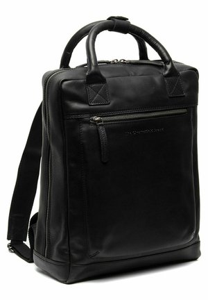 Sac à dos en cuir noir avec deux poignées supérieures, des bretelles ajustables, une poche zippée à l'avant et un design minimaliste. Texture lisse et matériel robuste.