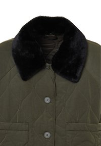 Gepolsterte olivgrüne Jacke mit einem schwarzen Kunstfellkragen, mit Knopfverschlüssen und einer Fronttasche. Weiche Textur und markante Nähte.