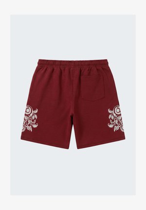 Shorts bordeaux à taille élastique avec motifs floraux blancs sur chaque jambe et une seule poche arrière du côté droit.