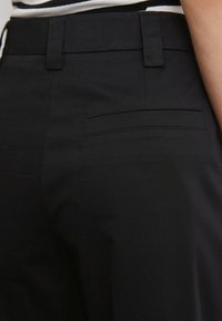 Zwarte broek met een gladde textuur, op maat gemaakt ontwerp en een enkele achterzak met subtiele stikdetails.