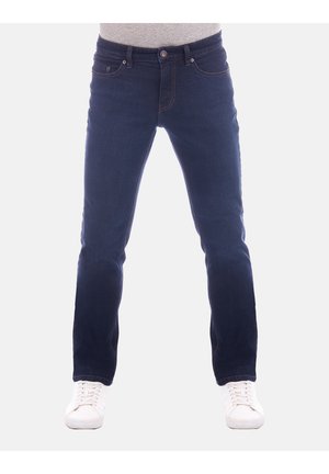 Dunkelblaue Jeans mit Slim-Fit, ausgestattet mit fünf Taschen und sichtbaren Nähten. Kombiniert mit weißen Sneakers und einem grauen Oberteil.