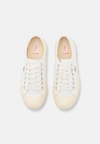 White canvas sneakers with a rubber toe cap, silver eyelets, and laces. Soft foam insole. Size 37 label visible. Textured rubber sole.