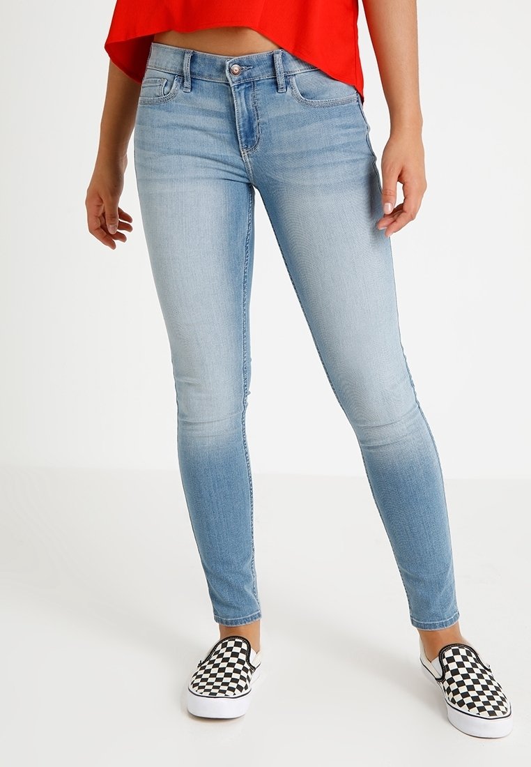 Ljusblå skinny jeans i denimtyg, med medelhög midja, subtil blekning och standard femfickdesign. Matchat med rutiga slip-on skor.