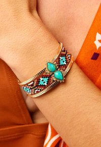Bracelet de poignet à perles multicolores avec des gemmes turquoises, présentant des motifs complexes en bleu, rouge et accents dorés.