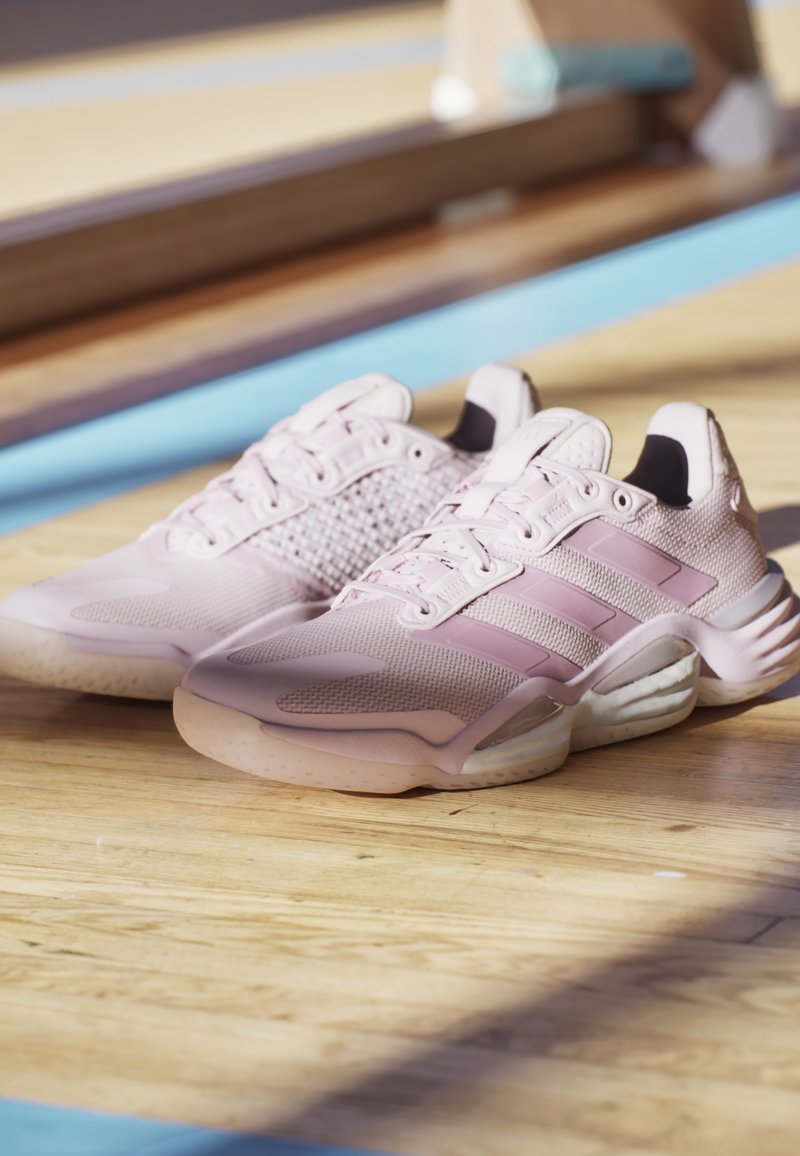 Zapatillas deportivas de malla y materiales sintéticos en rosa claro. Presentan una parte superior texturizada, un collar acolchado y tres franjas oscuras a los lados.